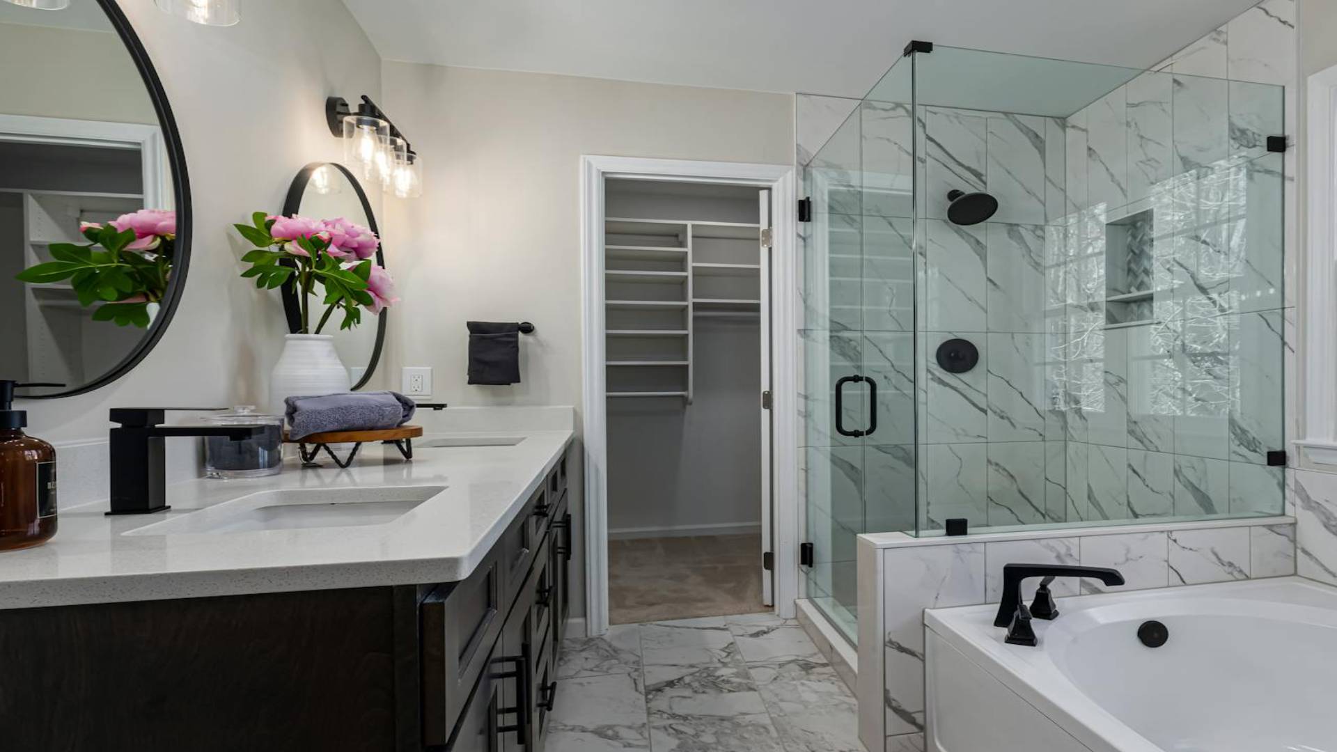 Bright white bathroom with a frameless glass shower door and matte black hardware