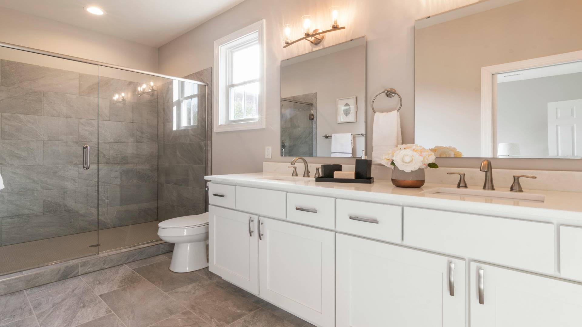 Light-filled bathroom with glass shower enclosure and vanity mirror