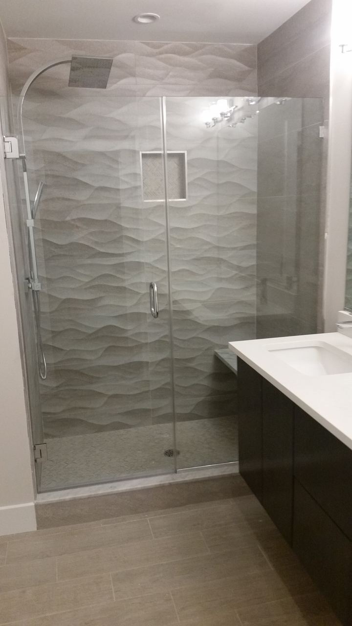 Replacement glass shower door in a tiled bathroom